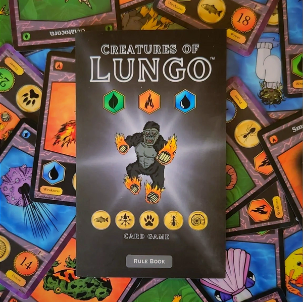 Creatures of Lungo Card Game - Rule Book. Creature cards are scattered beneath the rule book