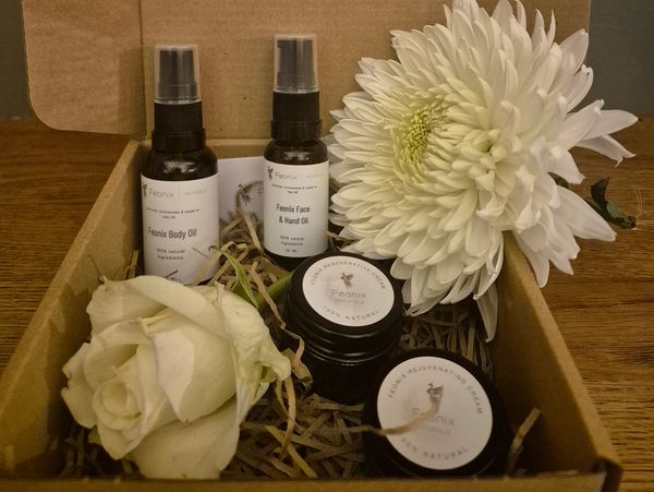Natural skincare set with oils and creams in a cardboard box with white flowers.