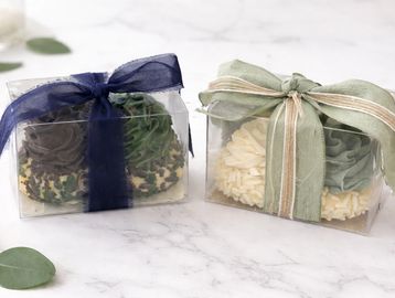 Two gift boxes with floral cupcakes, each tied with a decorative ribbon.