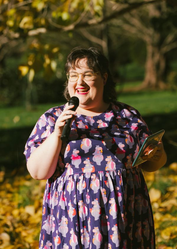 Smiling woman speaking into a microphone outdoors.