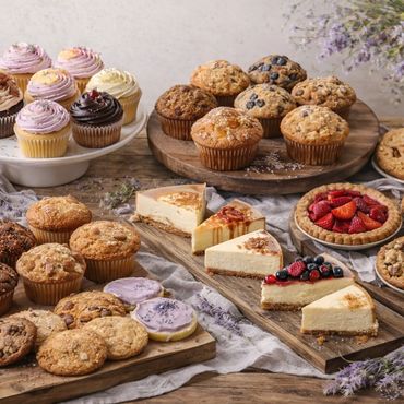 A variety of cupcakes, muffins, cookies, cheesecakes, and pies beautifully arranged on wooden boards.
