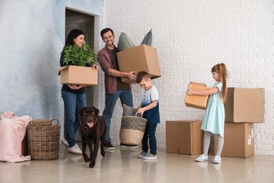 Family happily moving into a new home with boxes and a dog.