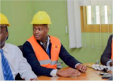 Men in safety helmets and vests sitting at a meeting table indoors.
