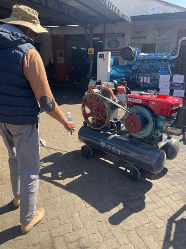 Man inspecting industrial machinery outdoors on a sunny day.