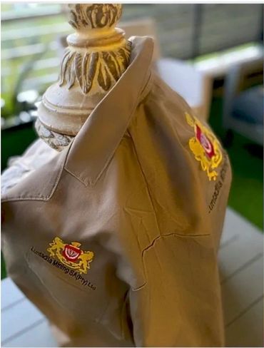 Beige work shirt with Luntsazia Mining SA logo draped over carved wooden furniture.