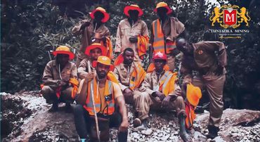 Group of miners in safety gear posing outdoors with Luntadila Mining logo.