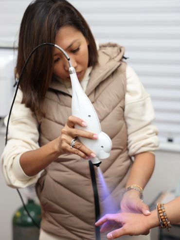 Woman performing light therapy on a hand.