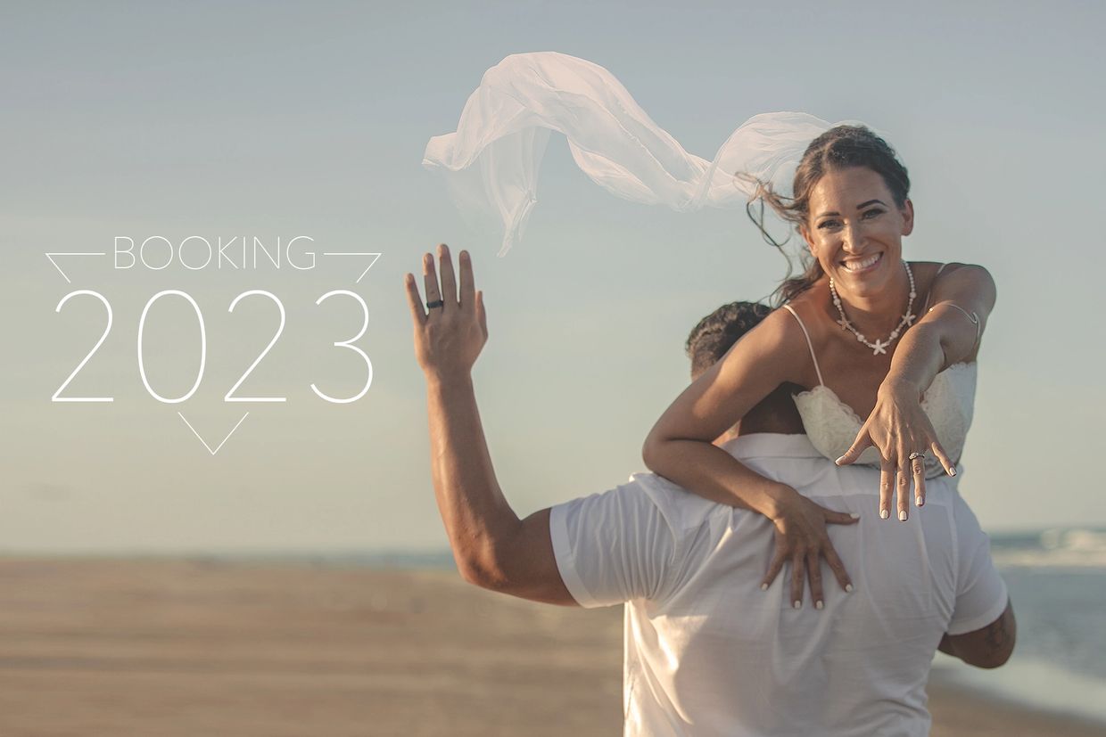 Joyful bride on groom's back at beach, showing ring and booking 2023.