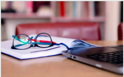 Books, reading glasses, and a laptop representing education and professional transcription training.