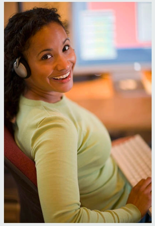 Smiling professional wearing a headset while working at a computer.