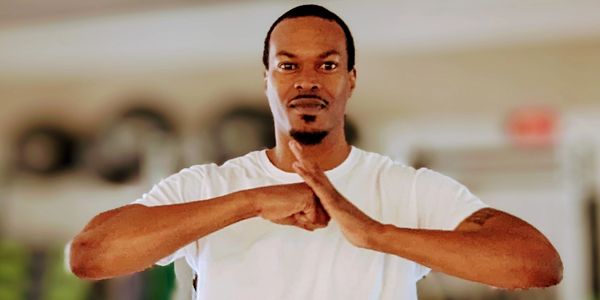 Man in white t-shirt showing a hand gesture.