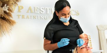 A professional beautician wearing gloves and a mask performs a facial treatment.