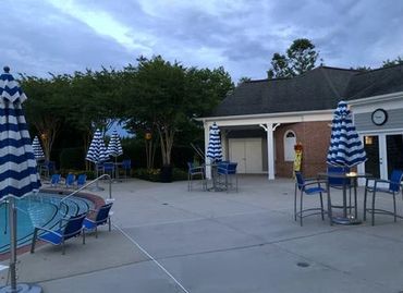 HOA pool area redesign with royal blue deck chairs that pop and fun striped umbrellas