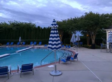 HOA pool area redesign with royal blue deck chairs that pop and fun striped umbrellas