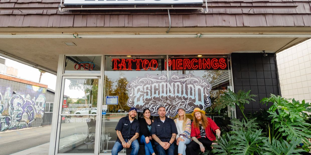 A view of a tattoo shop's exterior with five people sitting 