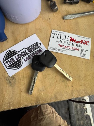 Two keys on a table with locksmith and flooring business cards nearby.