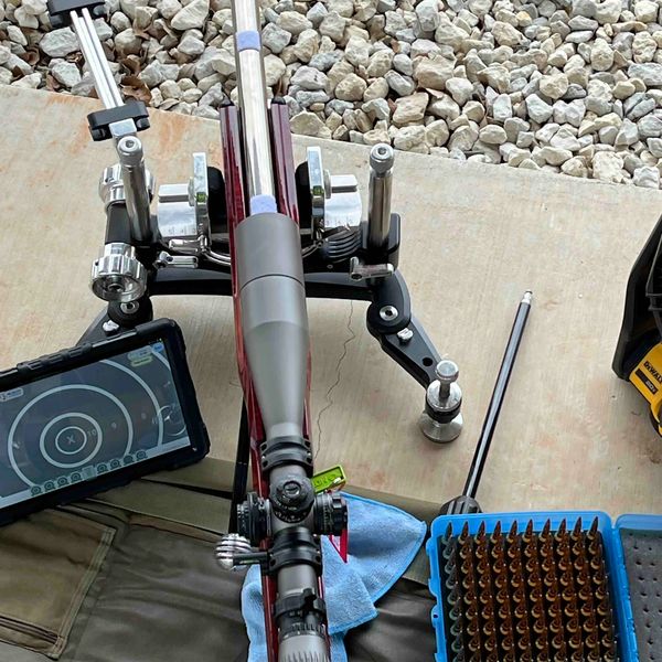 F-class rifle mounted on mechanical front rest with E-target display & match ammo beside the rifle