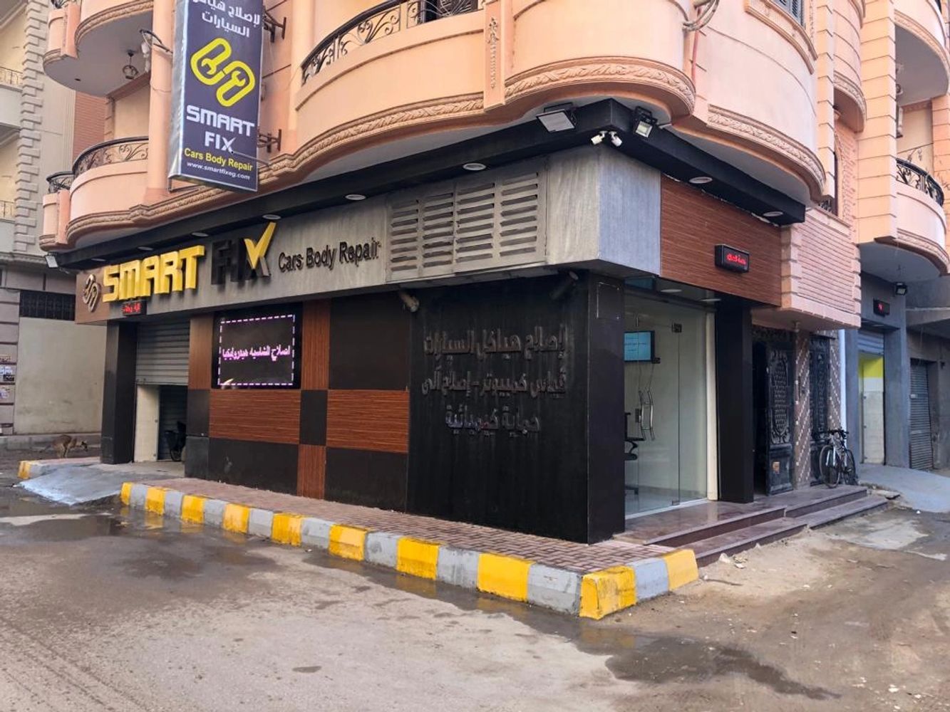 Smart Fix cars body repair shop on a street corner with yellow and white curb.