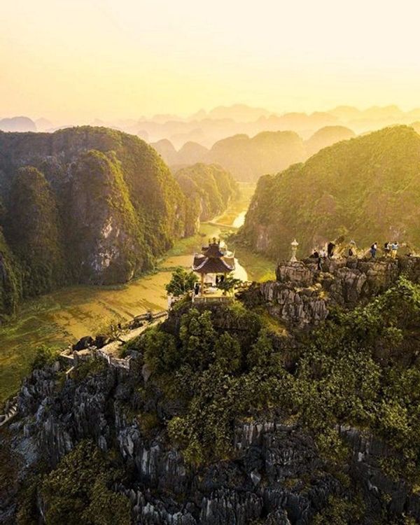 Scenic mountain temple surrounded by lush greenery at sunrise.
