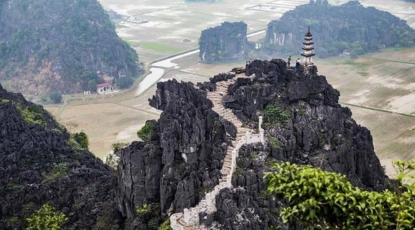 Stone staircase winding up a rocky mountain with a pagoda on top.