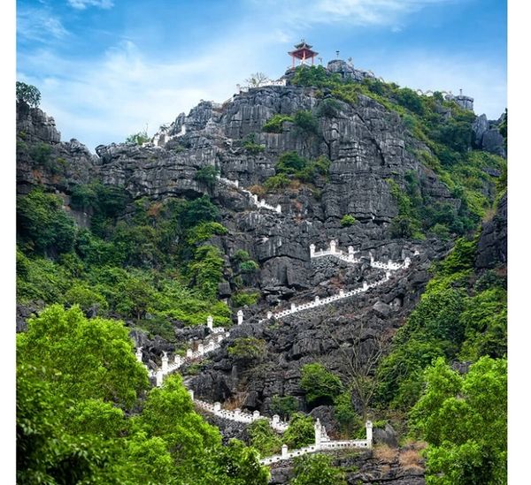 Staircase winding up a rocky mountain to a small pavilion at the top.