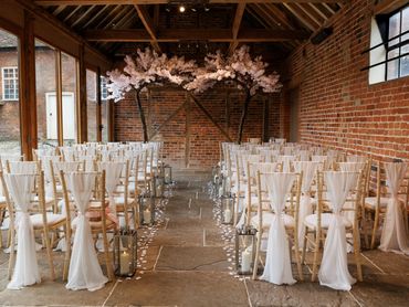 Wedding ceremony styling at Stanlake Park in Twyford with a blossom tree arch and chair sashes
