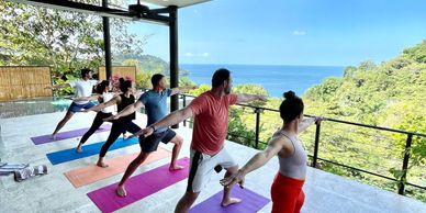 Group of people doing yoga on a luxury outdoor yoga deck with ocean view in the Costa Rican jungle