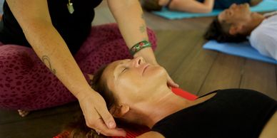 Woman in a black top receiving a reiki treatment from a woman in pink yoga pants and a black top