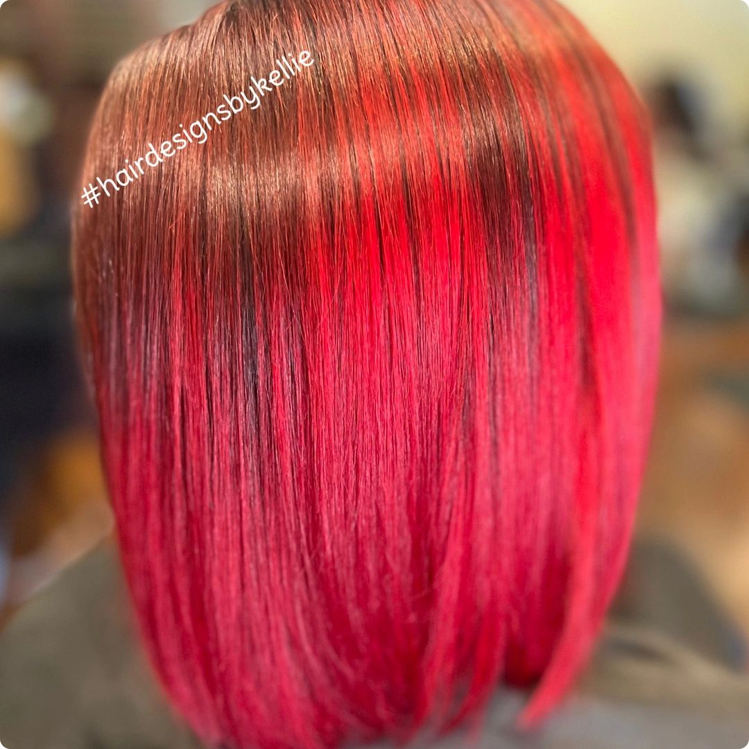 Sleek bob haircut with vibrant red and brown tones.