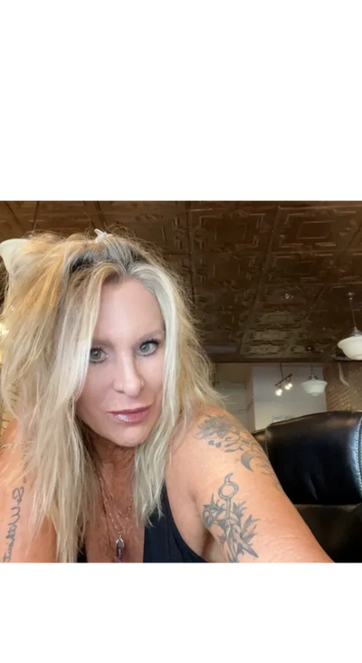 Woman with blonde hair and tattoos posing indoors.