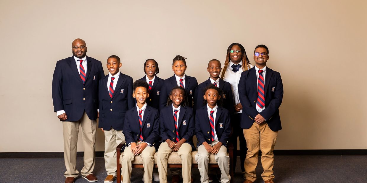 Group of students and teachers in matching blazers and ties posing for a formal photo.