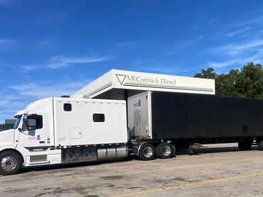 A white Volvo semi-truck with a black trailer parked at McCormick Diesel station.