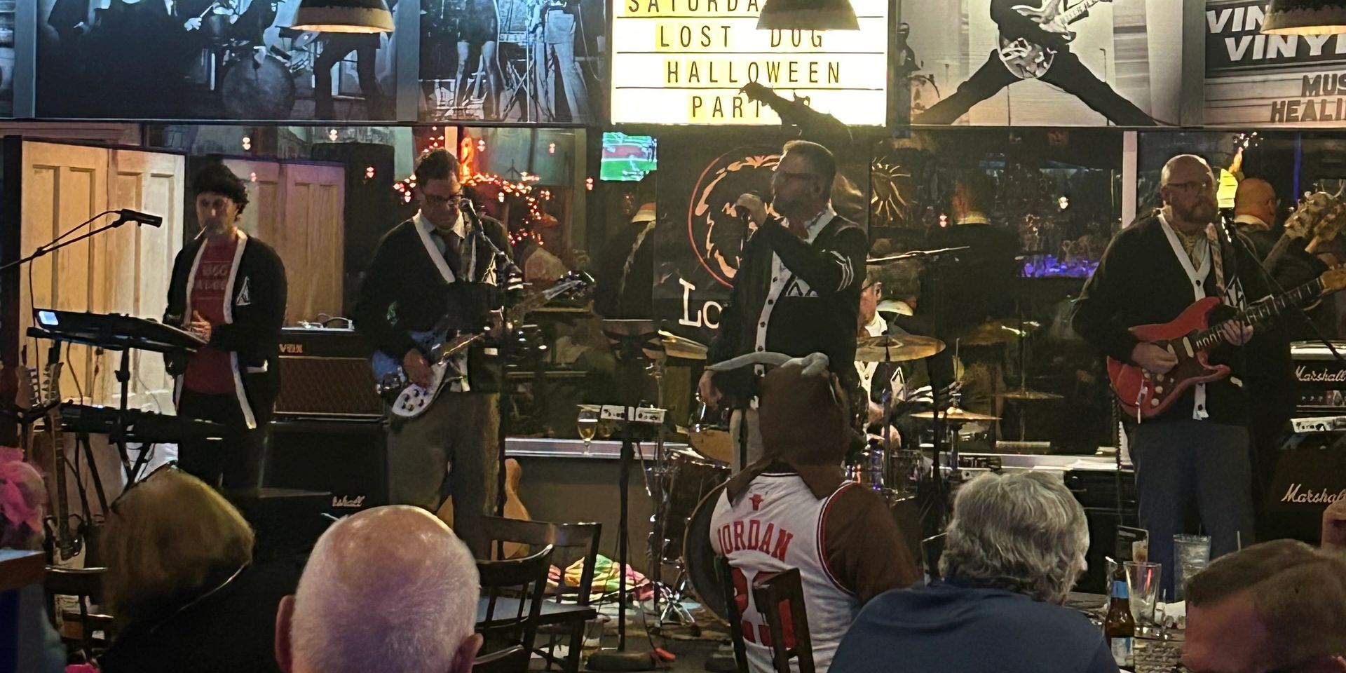 Band performing live on stage at a Halloween party in a cozy venue.