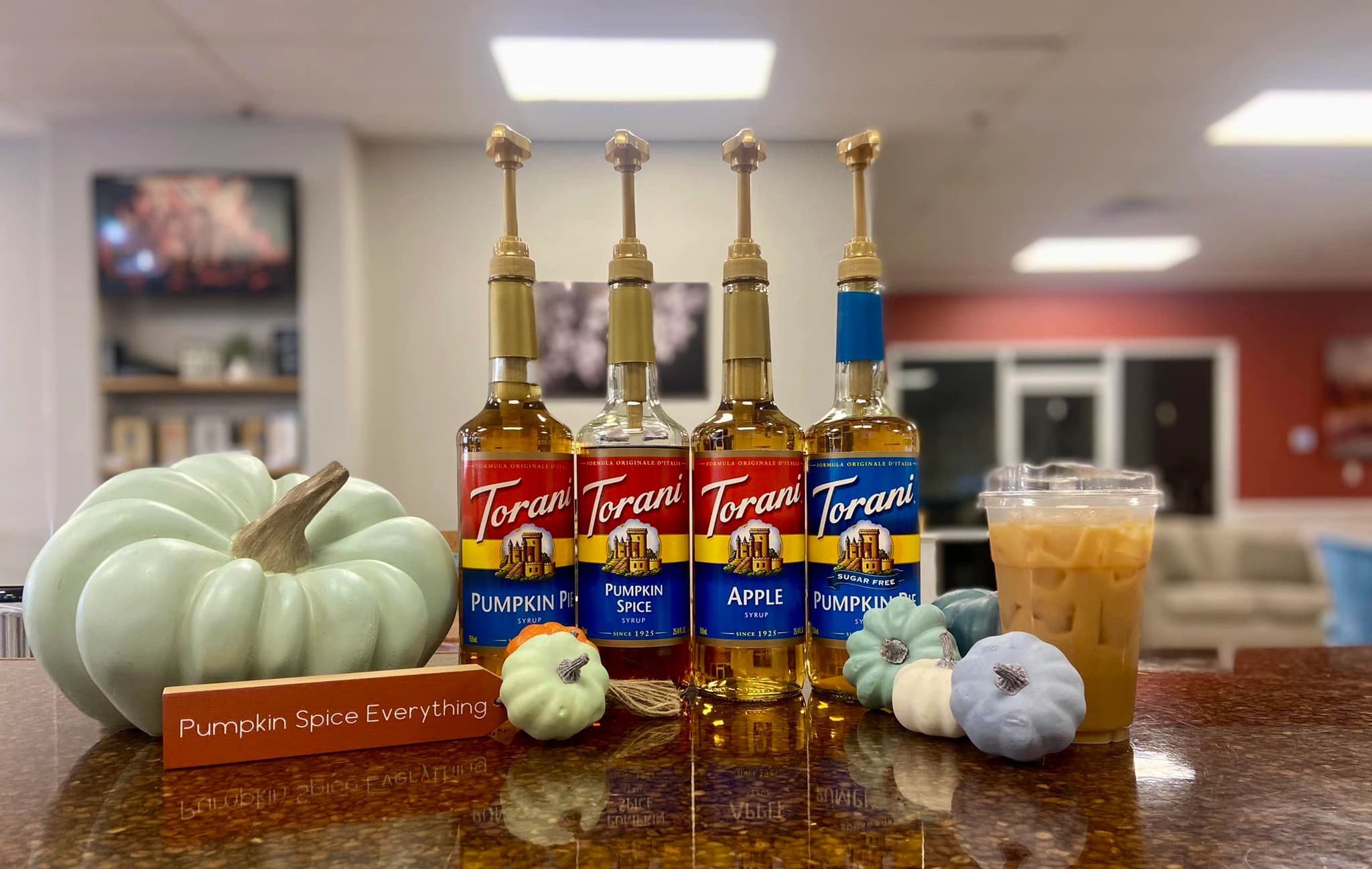 Pumpkin spice syrups with mini pumpkins and iced coffee.