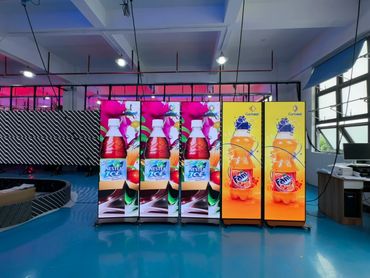 Large digital screens displaying Nestea Ice and Fanta bottles in a bright room.