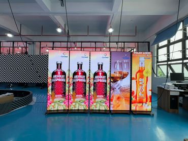 Bright digital advertising displays featuring Absolut Raspberri and Polar Limes bottles in a modern showroom.