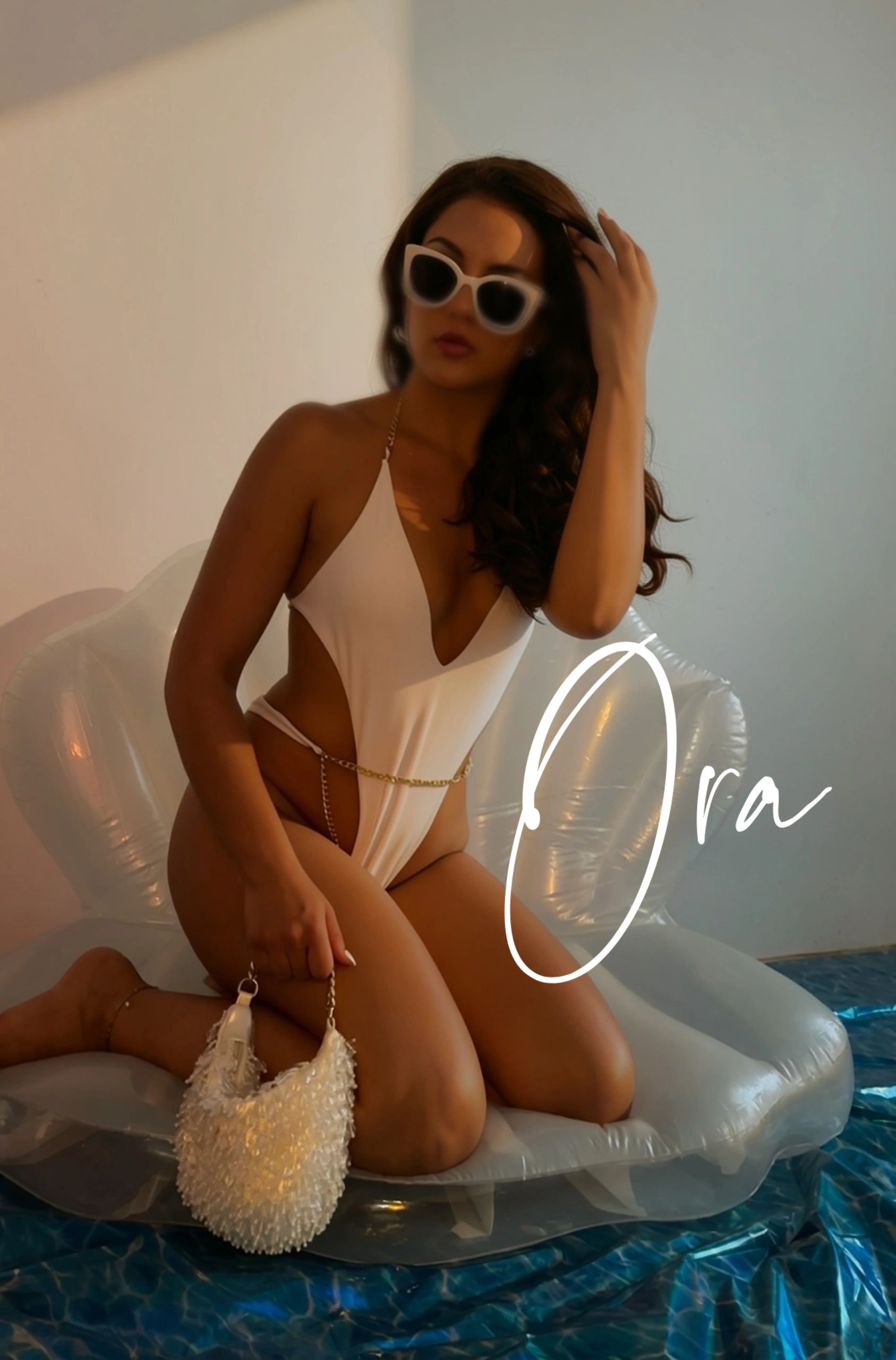 Femme en maillot blanc et lunettes de soleil sur un fauteuil gonflable.