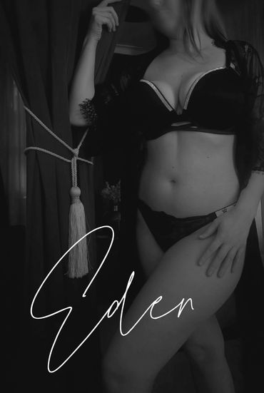 Woman in black lingerie posing by a red curtain with the name 'Eden' written.