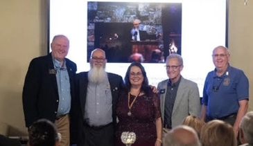 Five people posing in front of a screen during an event.