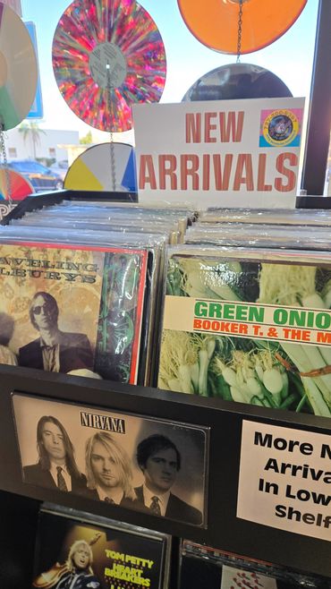 Vinyl records displayed under a 'New Arrivals' sign in a music store.