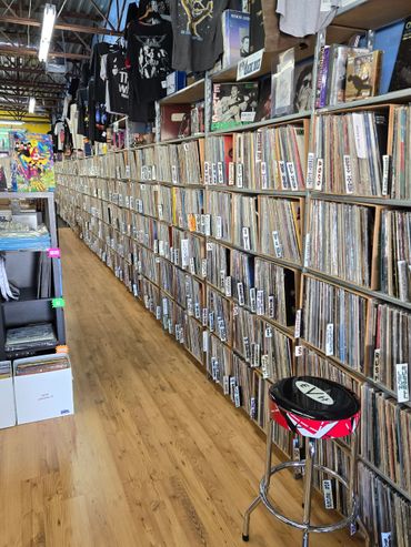 A long aisle of vinyl records and merchandise in a record store.