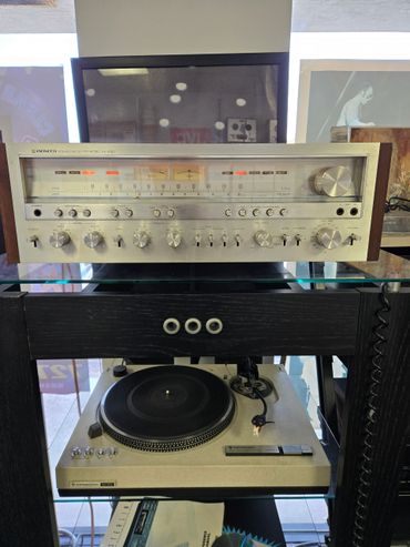 Vintage Pioneer stereo receiver and Kenwood turntable on a glass shelf.