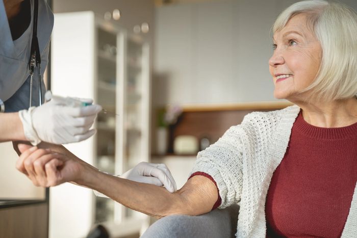 Elderly woman receiving a vaccine injection from a healthcare professional.