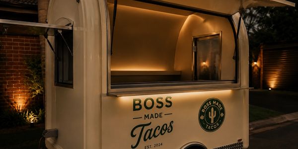 A cozy taco food truck named Boss Made Tacos lit up at night.