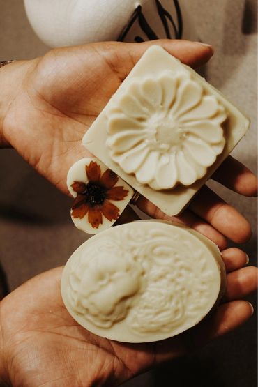 Hands holding intricately designed decorative soaps with floral and ornate patterns.