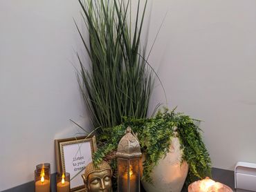 Zen corner with Buddha statue, candles, plants, and a motivational frame.