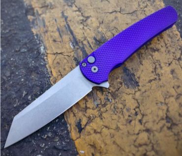 A folding knife with a purple textured handle on a cracked surface.