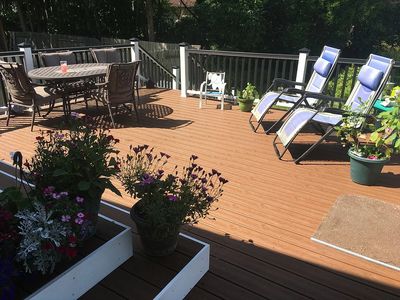 A wooden deck with patio furniture, featuring a dining table with chairs and two reclining chairs.