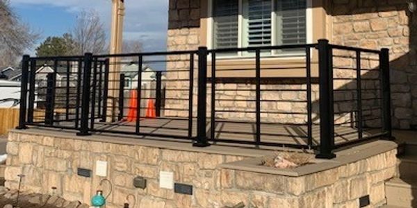 A stone house with a black metal railing, steps leading to the entrance.