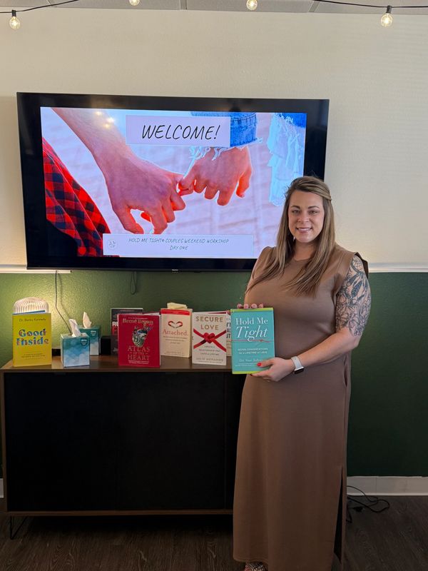 Woman presenting relationship book in Hold me Tight workshop setting.